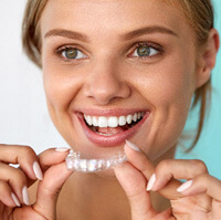 a woman removing her teeth whitening tray