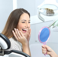 a dentist showing her patient their teeth whitening results