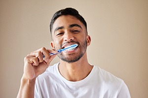 man brushing teeth for dental implant care in Plano