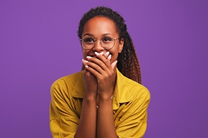 Laughing woman covering her teeth