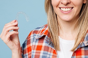 Smiling woman holding a clear aligner