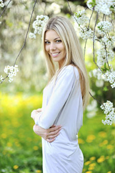 woman smiling outside by white flowers