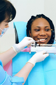 Dentist holding shade guide by woman’s teeth