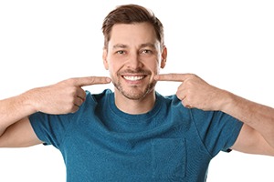 Man points to his smile with dental bridges in Plano