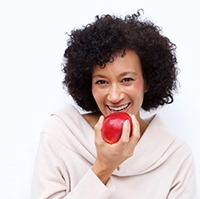 woman biting into a red apple