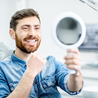 dental patient admiring his new smile in a mirror