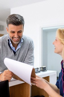 a front desk dental worker showing a patient a cost estimate for treatment