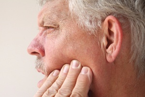 Man with dental implants in Plano, TX rubbing jaw in pain
