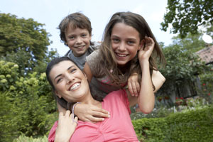 mother and two kids playing outside and smiling