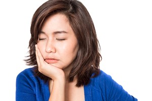 A young woman holding her cheek in pain