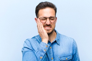 A man holding his cheek in pain