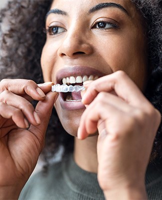 Woman placing Invisalign over upper arch