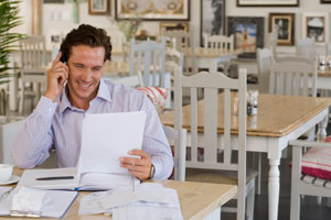 man at table looking at paperwork and on the phone