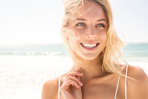 A woman smiling on a beach.