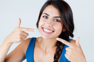 woman smiling while pointing at teeth 