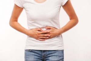 A woman clutching her stomach ache in pain.