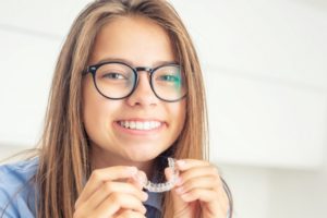 teen girl putting Invisalign on just her top teeth