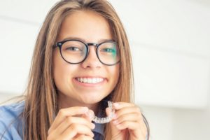 teen girl putting Invisalign on just her top teeth 