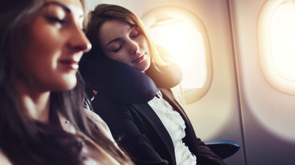 Woman in airplane seat with neck pillow sleeping